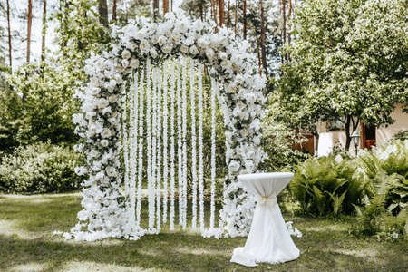Wedding ceremony in nature with an arch decorated with white flowersの写真素材