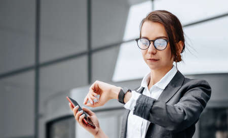 A business woman checks the time in the city during a working day waiting for a meeting. Discipline and timing. An employee goes towards a corporate meeting.の写真素材