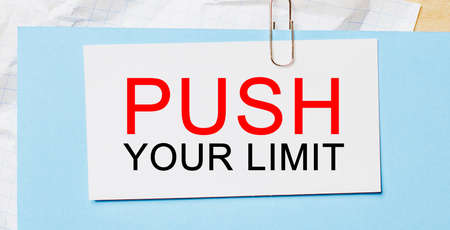 Text PUSH YOUR LIMIT on a white card on a blue background. Business conceptの写真素材