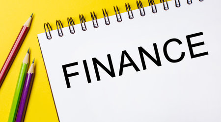 FINANCE on a white notepad with pencils on a yellow background. Business conceptの写真素材