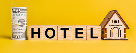 HOTEL with house miniature model and money on a yellow background. The concept of business, finance, credit, tax , real estate, home, housingの写真素材