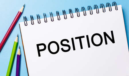Text POSITION on a white notepad with pencils on a blue background. Business conceptの写真素材