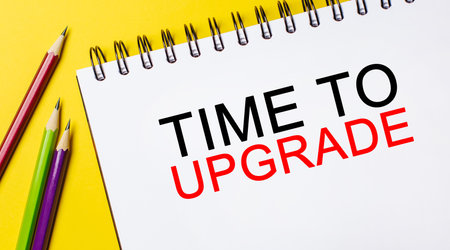 Text Time to upgrade on a white notepad with pencils on a yellow background. Business conceptの写真素材