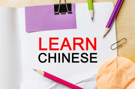 Text Learn Chinese on a white notepad with pencils on a wooden background. Business conceptの写真素材