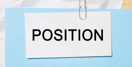 Text POSITION on a white card on a blue background. Business conceptの写真素材