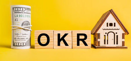 OKR with house miniature model and money on a yellow background. Investment, real estate, home, housing, earnings, financial conceptの写真素材
