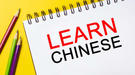Learn Chinese on a white notepad with pencils on a yellow background. Business conceptの写真素材