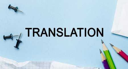 Text TRANSLATION on a white notepad with pencils on a blue background. Business conceptの写真素材