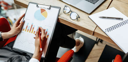 Business woman checks charts and refreshes financial progress. The girl analyzes the business model in the workplace.の写真素材