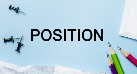 Text POSITION on a white notepad with pencils on a blue background. Business conceptの写真素材