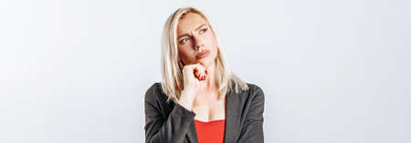 Beautiful young girl unhappy frown and thinks on gray isolated backgroundの写真素材