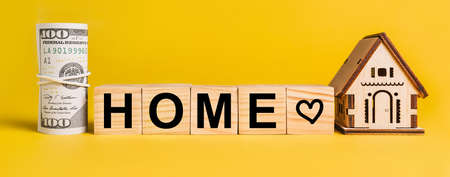 HOME with house miniature model and money on a yellow background. The concept of business, finance, credit, tax , real estate, home, housingの写真素材
