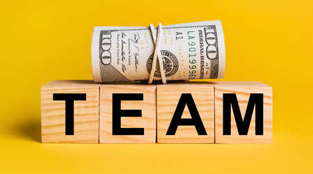TEAM with money on a yellow background. The concept of business, finance, credit, income, savings, investments, exchange, taxの写真素材