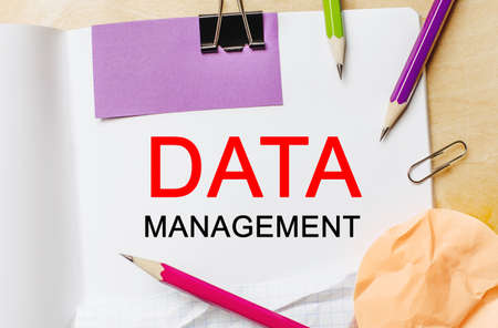 Text DATA MANAGEMENT on a white notepad with pencils on a wooden background. Business conceptの写真素材