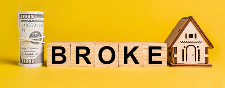 BROKE with house miniature model and money on a yellow background. The concept of business, finance, credit, tax , real estate, home, housingの写真素材