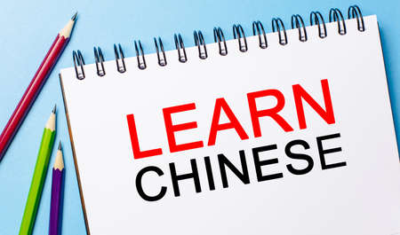 Learn Chinese on a white notepad with pencils on a blue background. Business conceptの写真素材