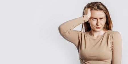 Beautiful young girl posing looking at the camera on a white isolated background. Serious brunette woman ignores covers her ears with her hands and closes her eyes, does not see and does not hearの写真素材
