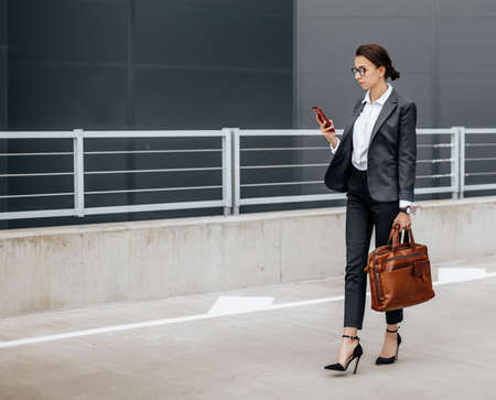 A business woman checks the time in the city during a working day waiting for a meeting. Discipline and timing. An employee goes towards a corporate meeting.の写真素材
