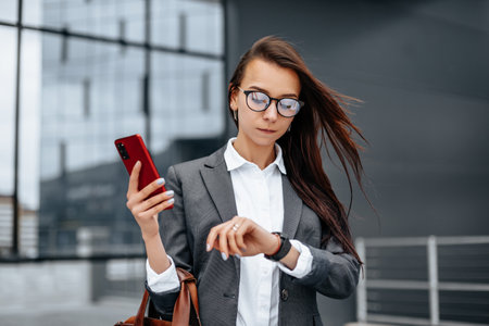 A business woman checks the time in the city during a working day waiting for a meeting. Discipline and timing. An employee goes towards a corporate meeting.の写真素材
