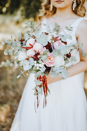 Bride holding wedding bouquet with red and pink flowersの写真素材