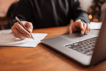 Handsome man working on laptop in the workplace. Businessman typing information on computer at work table with notepad