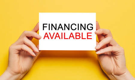 Female hands hold card paper with text Financing Available on a yellow background. Business and finance conceptの写真素材