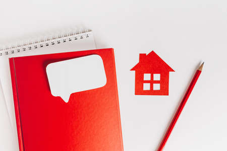 Sweet home. Estimating and paying house tax. Mock up with red house, notepad and sticker in copy space white backgroundの写真素材