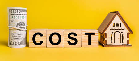 COST with house miniature model and money on a yellow background. The concept of business, finance, credit, tax , real estate, home, housingの写真素材