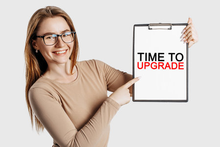 Time to upgrade. Beautiful young business woman wearing glasses holds a clipboard with mock up space isolated on gray backgroundの写真素材