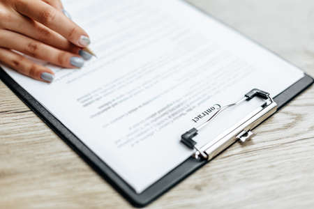 Young girl office worker or business lady signs documents. Concentrated businesswoman working with papers. Business conceptの写真素材
