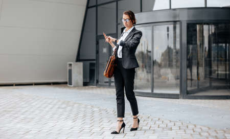 A business woman checks the time in the city during a working day waiting for a meeting. Discipline and timing. An employee goes towards a corporate meeting.の写真素材