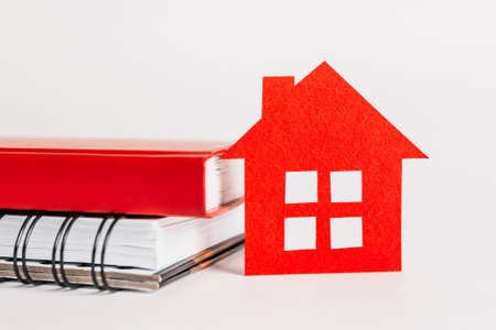 Sweet home. Estimating and paying house tax. Mock up with red house, notepad and sticker in copy space white backgroundの写真素材