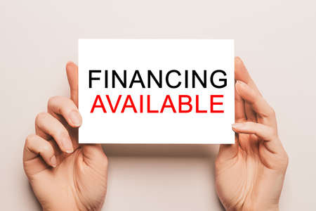 Female hands hold card paper with text Financing Available on a yellow background. Business and finance conceptの写真素材