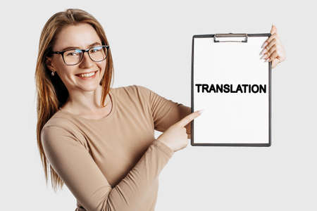 TRANSLATION. Beautiful young business woman wearing glasses holds a clipboard with mock up space isolated on gray backgroundの写真素材