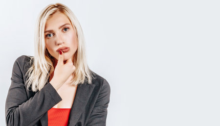 The woman thought about the choice and furrowed her eyebrows. Young beautiful blonde girl holds a hand to the face thinks and makes a decision. Place for advertising. What to chooseの写真素材