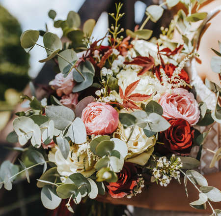 Bride holding wedding bouquet with red and pink flowersの写真素材