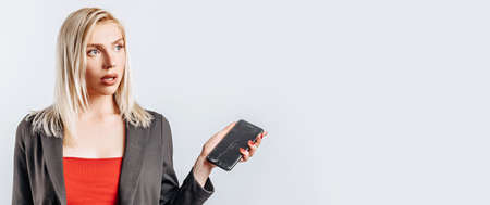 Beautiful young girl unhappy and holding phone on gray isolated backgroundの写真素材