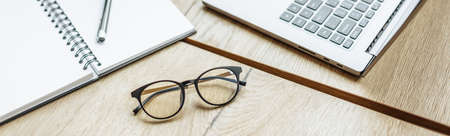 Glasses at the workplace in the office near the laptop and notepad. Business hoursの写真素材