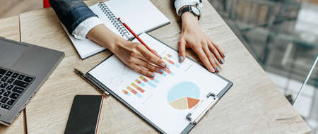 Business woman checks charts and refreshes financial progress. The girl analyzes the business model in the workplace.の写真素材