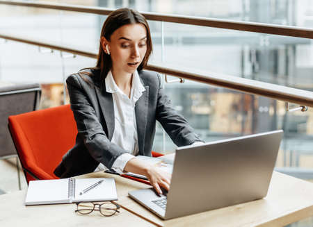 Girl works on a laptop in the workplace. Businesswoman is shocked by the crisis. Successful woman creates a startup and makes decisions.の写真素材