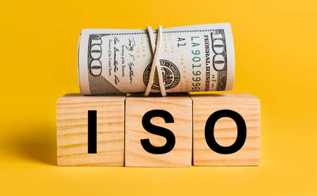 ISO with money on a yellow background. The concept of business, finance, credit, income, savings, investments, exchange, taxの写真素材
