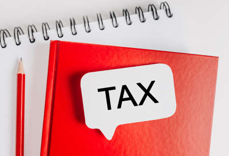 Text Tax on a white sticker with office stationery background. Flat lay on business, finance and development conceptの写真素材