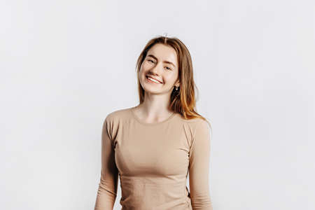 Beautiful young girl smiling and posing looking at the camera on a white isolated background. Positive brunette woman. Kind look. Beauty face.の写真素材