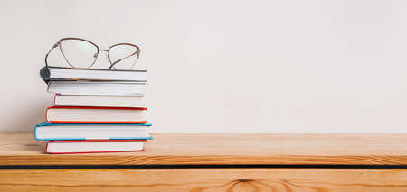 A stack of books and glasses on the table. Mock up with education and reading concept. Literature...