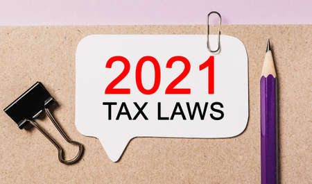 Text 2021 tax laws on a white sticker with office stationery background. Flat lay on business, finance and development conceptの写真素材