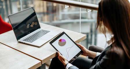 Business woman checks charts and refreshes financial progress. The girl analyzes the business model in the workplace.の写真素材