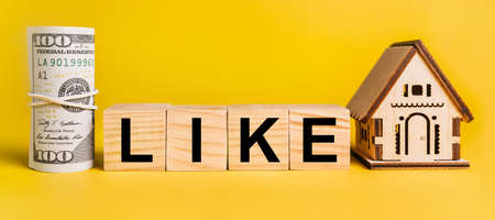 LIKE with house miniature model and money on a yellow background. The concept of business, finance, credit, tax , real estate, home, housingの写真素材