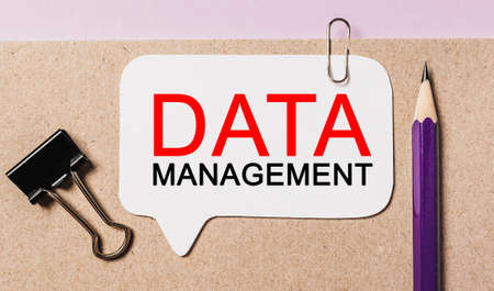 Text DATA MANAGEMENT on a white sticker with office stationery background. Flat lay on business, finance and development conceptの写真素材