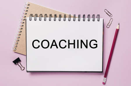 Text COACHING on a white sticker with office stationery background. Flat lay on business, finance and development conceptの写真素材