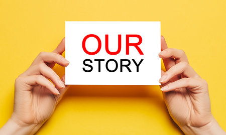 Female hands hold card paper with text Our Story on a yellow background. Business and finance conceptの写真素材